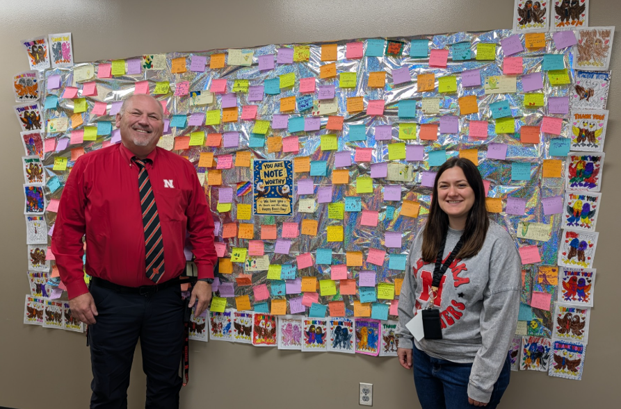 Principal and Dean of Students stand by a poster made by students with kind words on sticky notes.