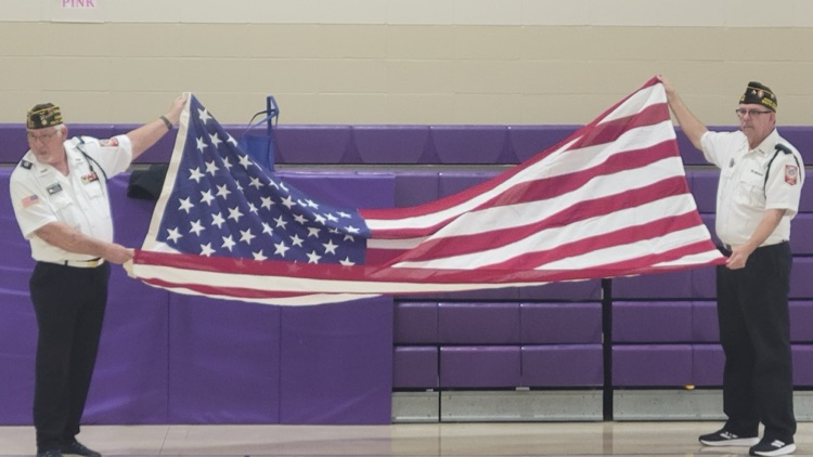 two men begin to fold United States flag
