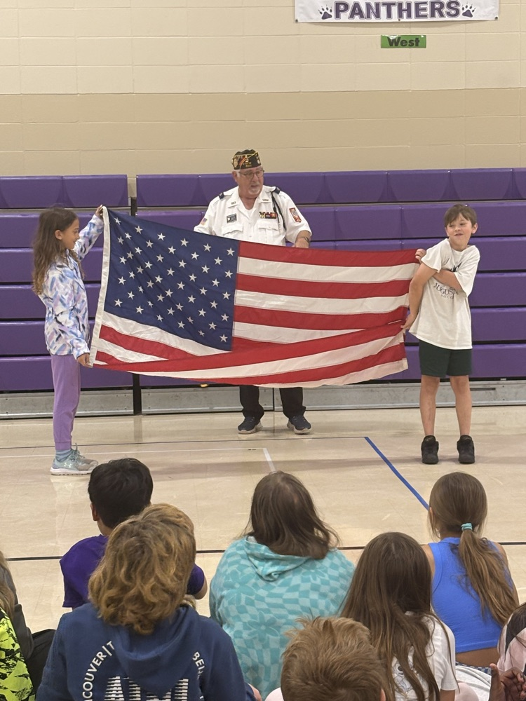 man teaches two children how to properly fold the United States flag