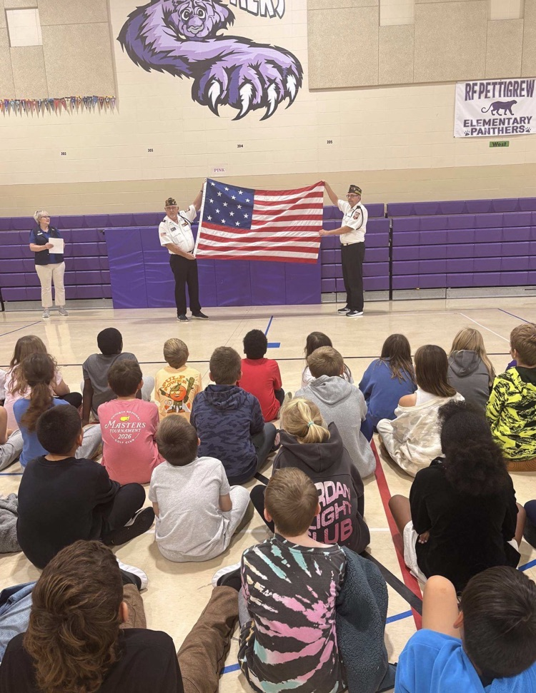 children watch as two men hold up the United States flag