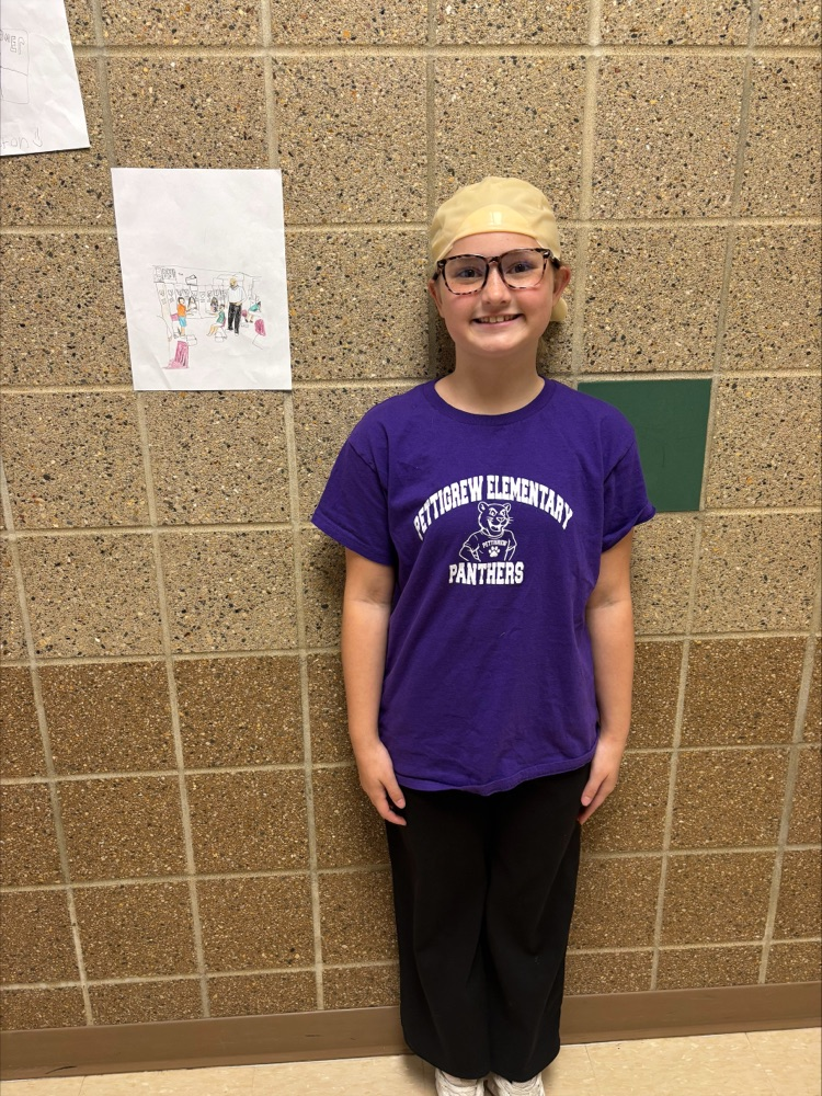 student with a bald wig standing next to her artwork 