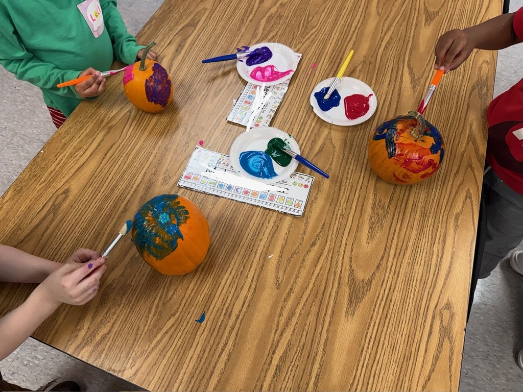 Three students painting a pumpkin