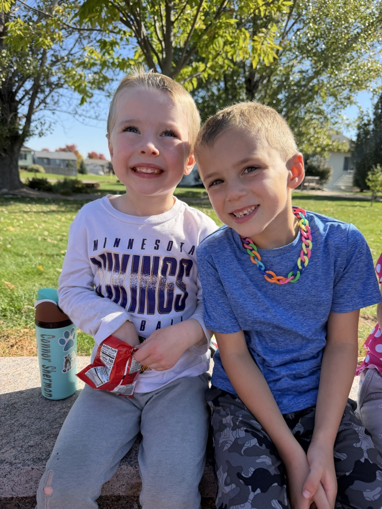 two students having snacks and water at the outdoor classroom seating area