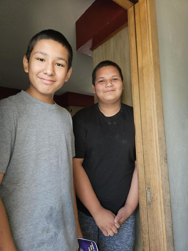 Two young boys stand in a doorway smiling 
