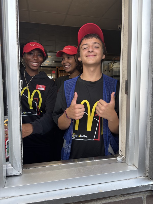 Three young mcdonald's workers stand in drive through line giving thumbs up