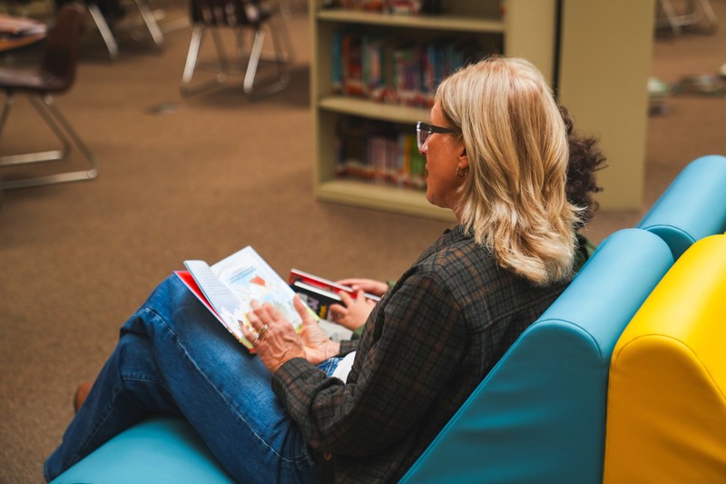 A volunteer reads to students in a library