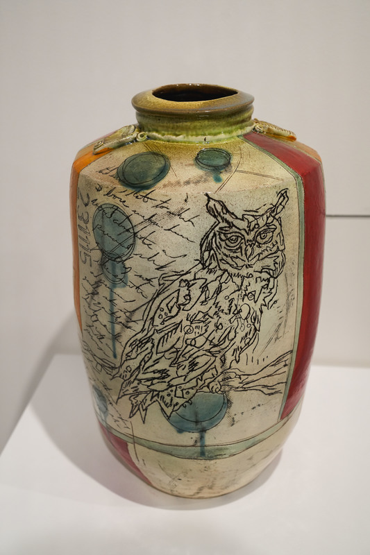 Owl design etched in to a painted vase sits on top of a white  case as part of an SFSD art educator exhibit at the Washington Pavilion