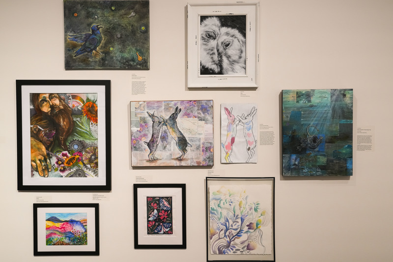 Colorful works of art hang on a white wall as part of a teacher art exhibit at the Washington Pavilion