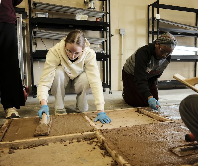 Two women smooth out concrete as part of Pizza Pop and Power tools day