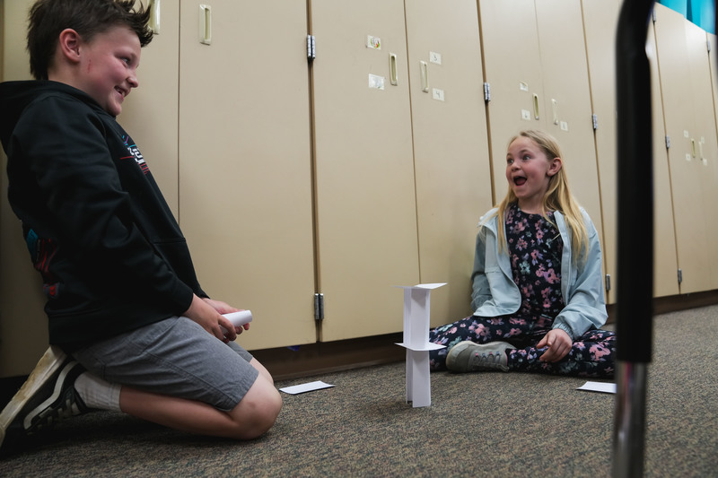Students excitedly react as they build a model out of paper cards
