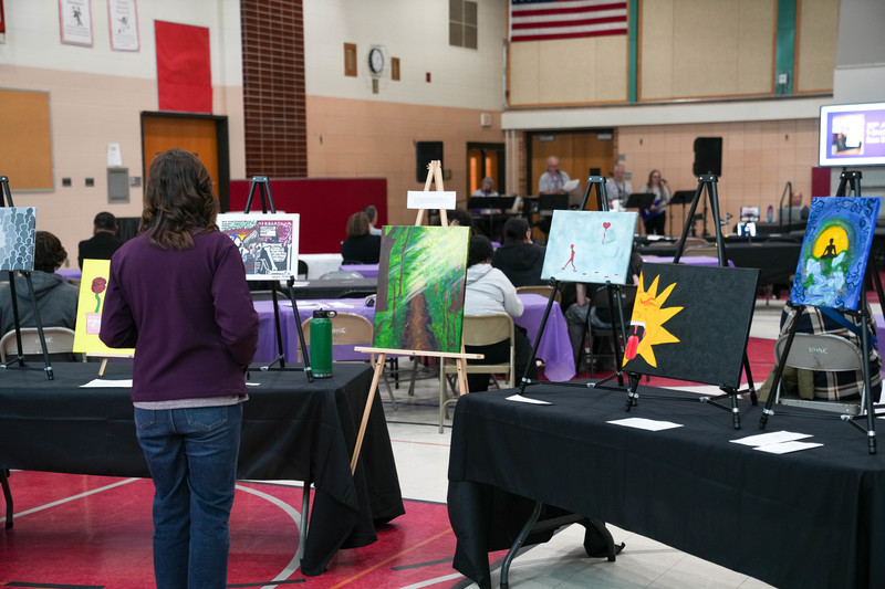 A woman looks at artwork created by students at Joe Foss as a band plays in the background