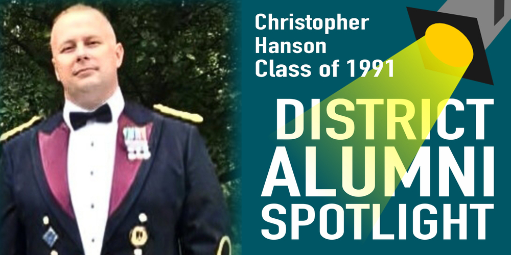 Graphic titled “District Alumni Spotlight” featuring Christopher Hanson, Class of 1991. The design includes a spotlight graphic shining on the text. On the left, there is a photo of Christopher Hanson dressed in formal military attire with medals on his jacket, standing outdoors with trees in the background.