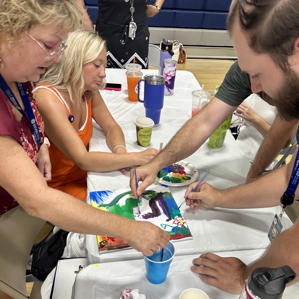 Group working together on a shared painting, adding colors with brushes.