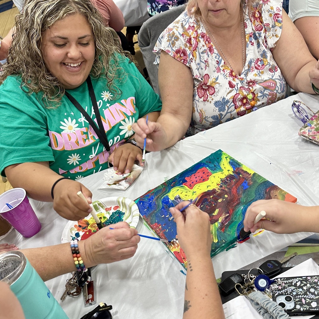 Woman smiling and painting with others at a colorful group art activity.