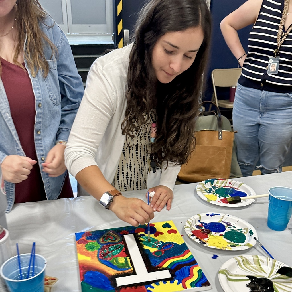 Woman focused on painting colorful designs on a canvas.