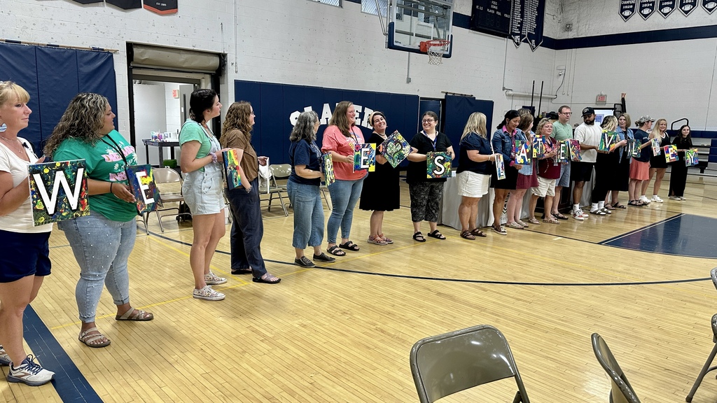 Group lined up in the gym holding painted canvases that spell “We are Slate Valley.”
