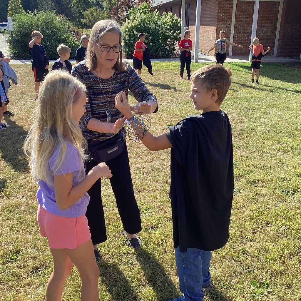 Teacher guiding students as they pass a magic ring during an outdoor activity.