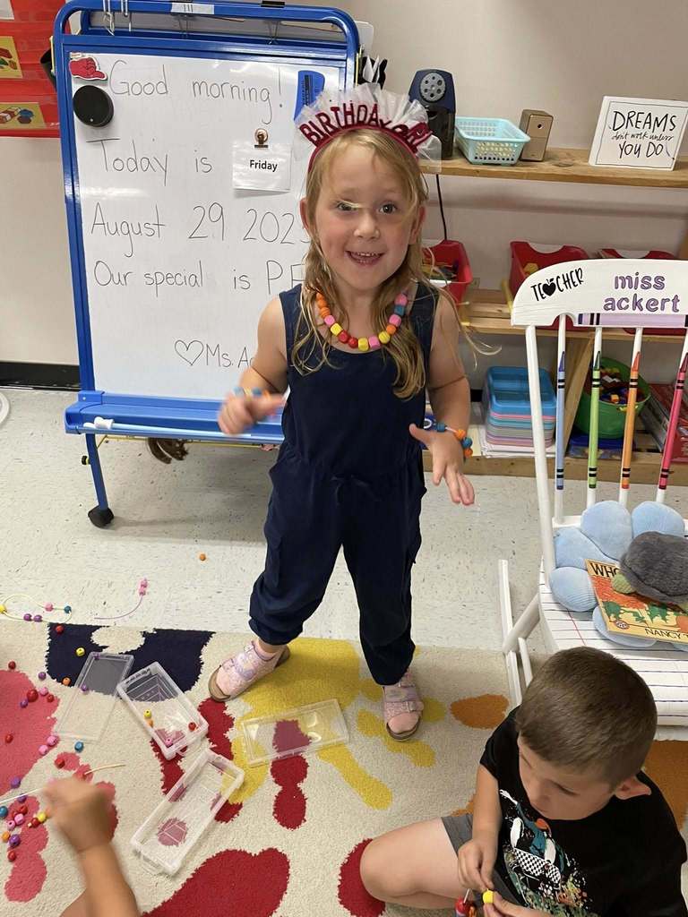 Kindergarten students practice switching between learning stations with bead activities.