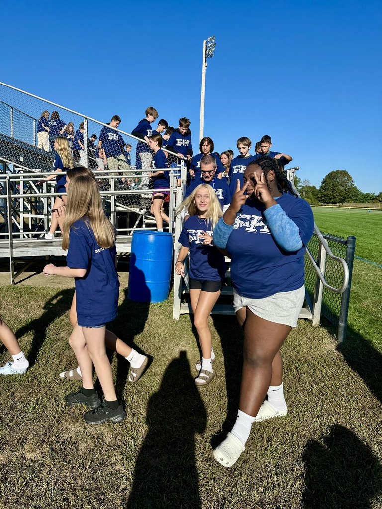 Students walk down bleacher steps, one smiling and flashing a peace sign at the camera.