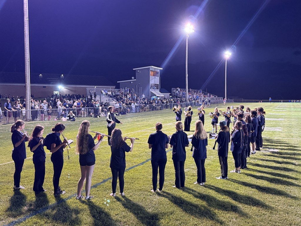 Band members play instruments while facing the stands filled with spectators.