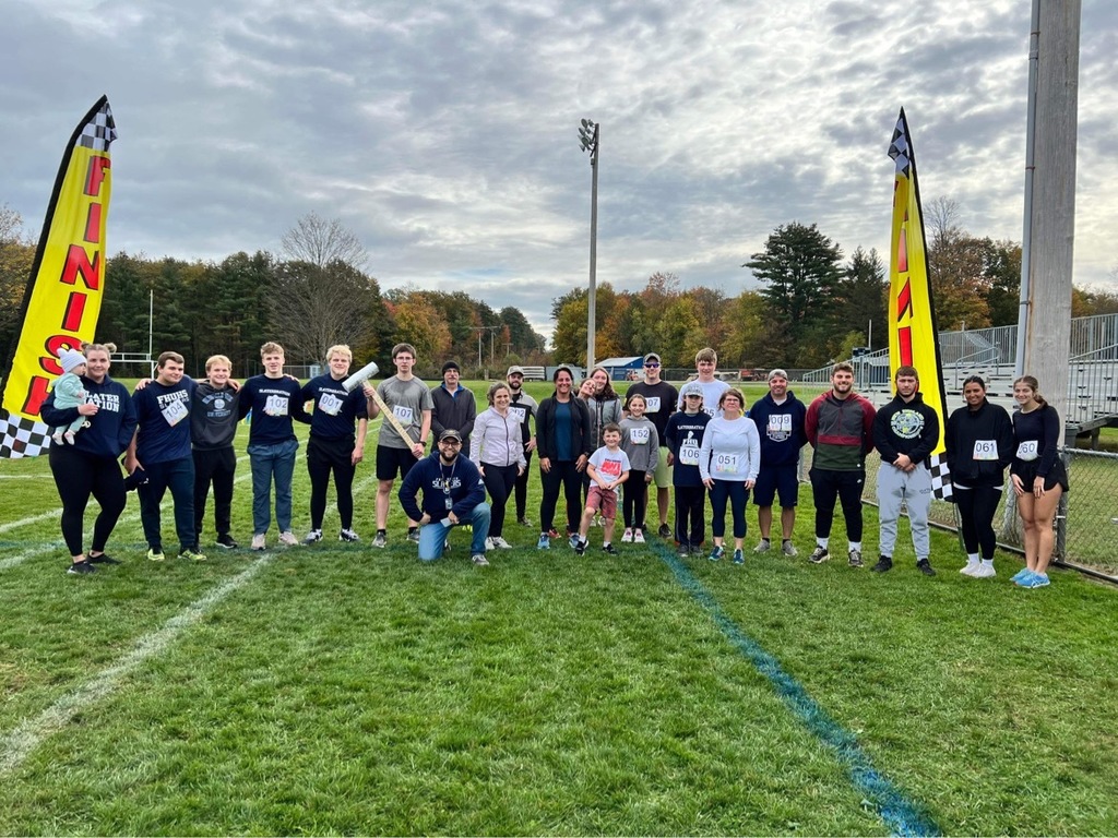 Runners and supporters gather at the Slater 5K finish line with fall foliage in the background.