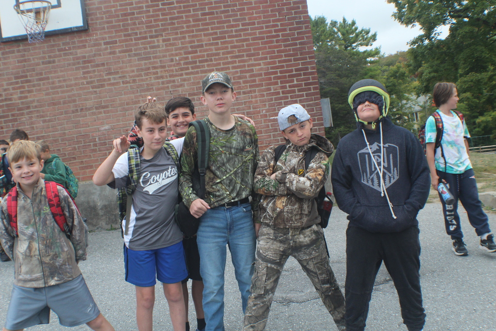 A group of five boys pose for a photo outside a brick building.