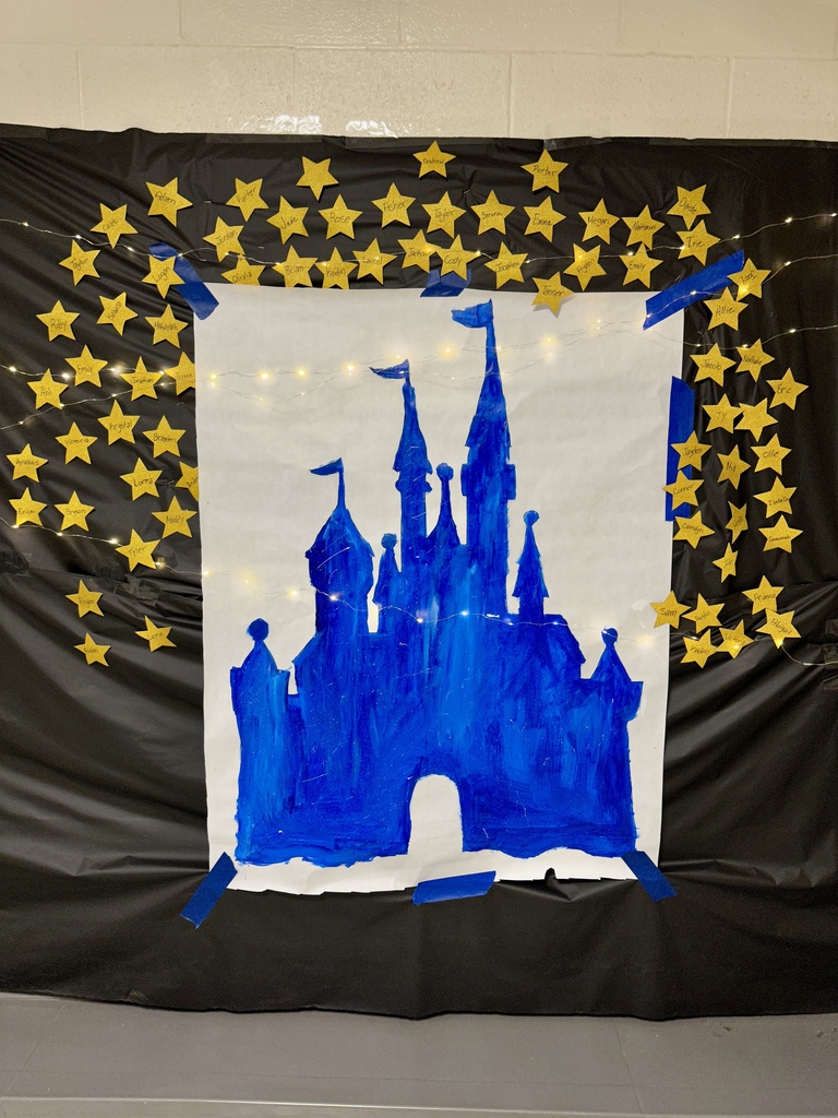A blue hand-painted Disney-style castle on white paper, surrounded by yellow star cutouts with names written on them and string lights.