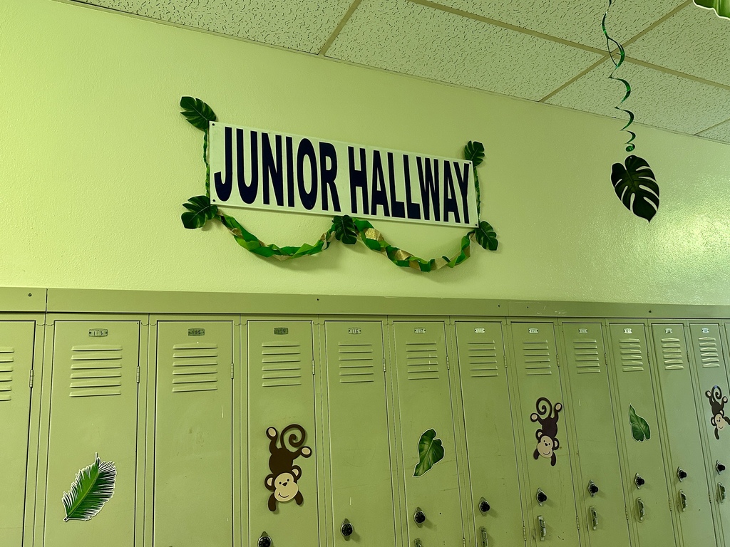 A sign reading “Junior Hallway” above lockers, decorated with jungle leaves and cutouts of monkeys and foliage.