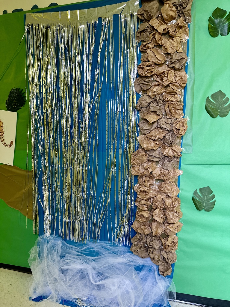 A hallway decoration showing a waterfall made of silver fringe, blue fabric, and brown crumpled paper rocks with white tulle at the base.