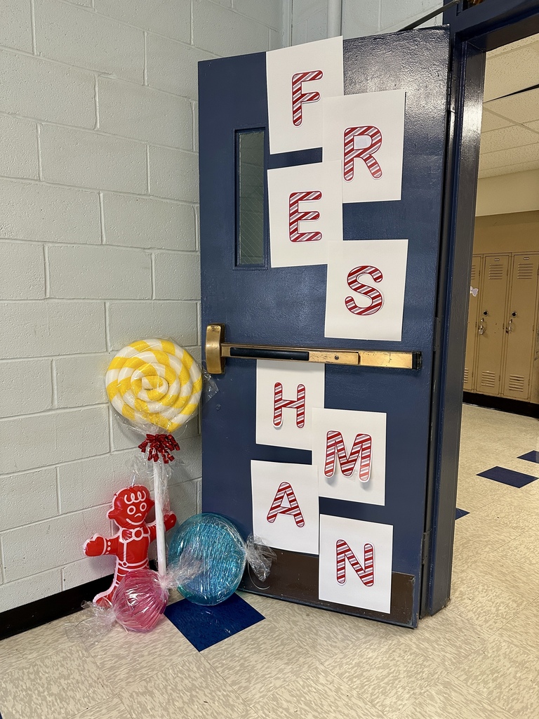 A classroom door decorated with large letters spelling “Freshman” in red candy cane stripes, surrounded by oversized lollipop and candy props.