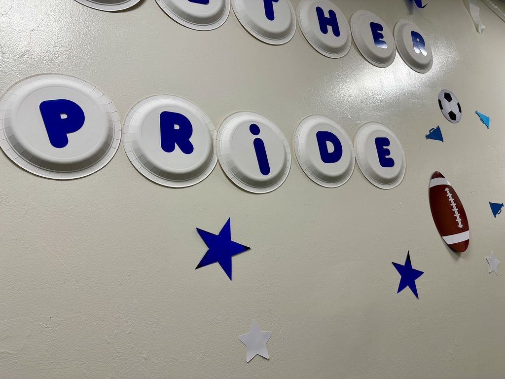 Wall display spelling “Slater Pride” with blue letters on paper plates, decorated with stars, a football, and a soccer ball.