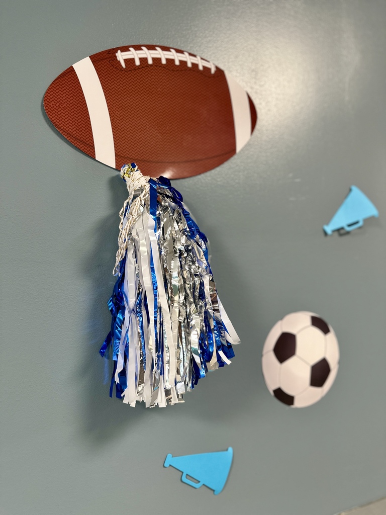 Wall decorations featuring a paper football with attached blue and silver pom-poms, a soccer ball, and small megaphones.