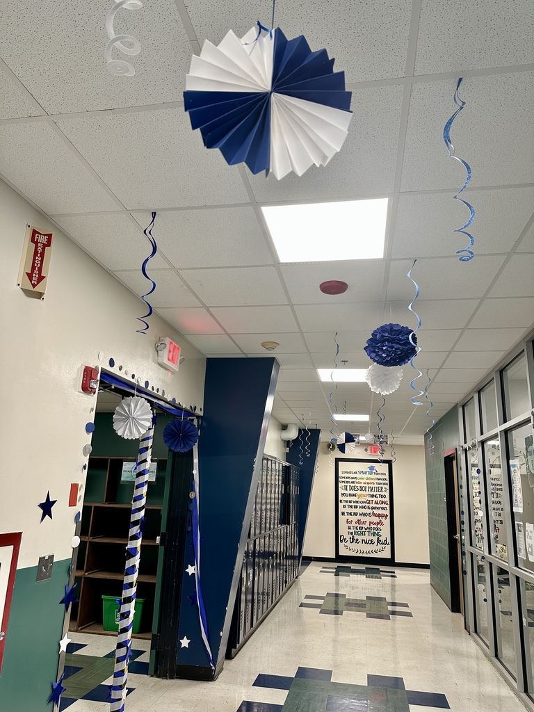 School hallway decorated in blue and white with hanging streamers, stars, and paper fans.