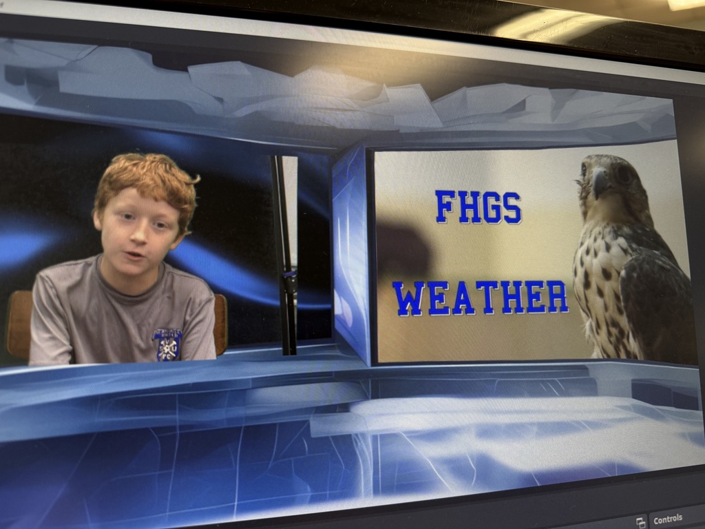 A boy wearing a grey shirt sits on a chair. He is in front of a blue screen with a digital overlay that says "FHGS WEATHER" next to an image of a falcon