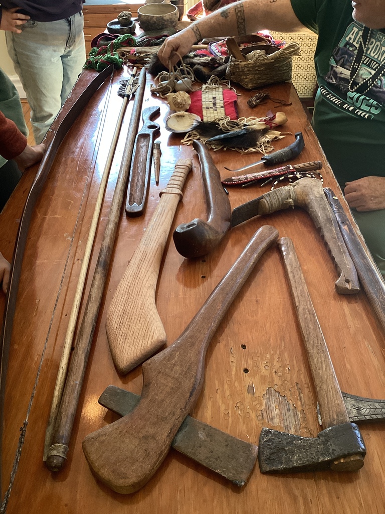 Close-up of a table displaying wooden tools, woven items, and artifacts.
