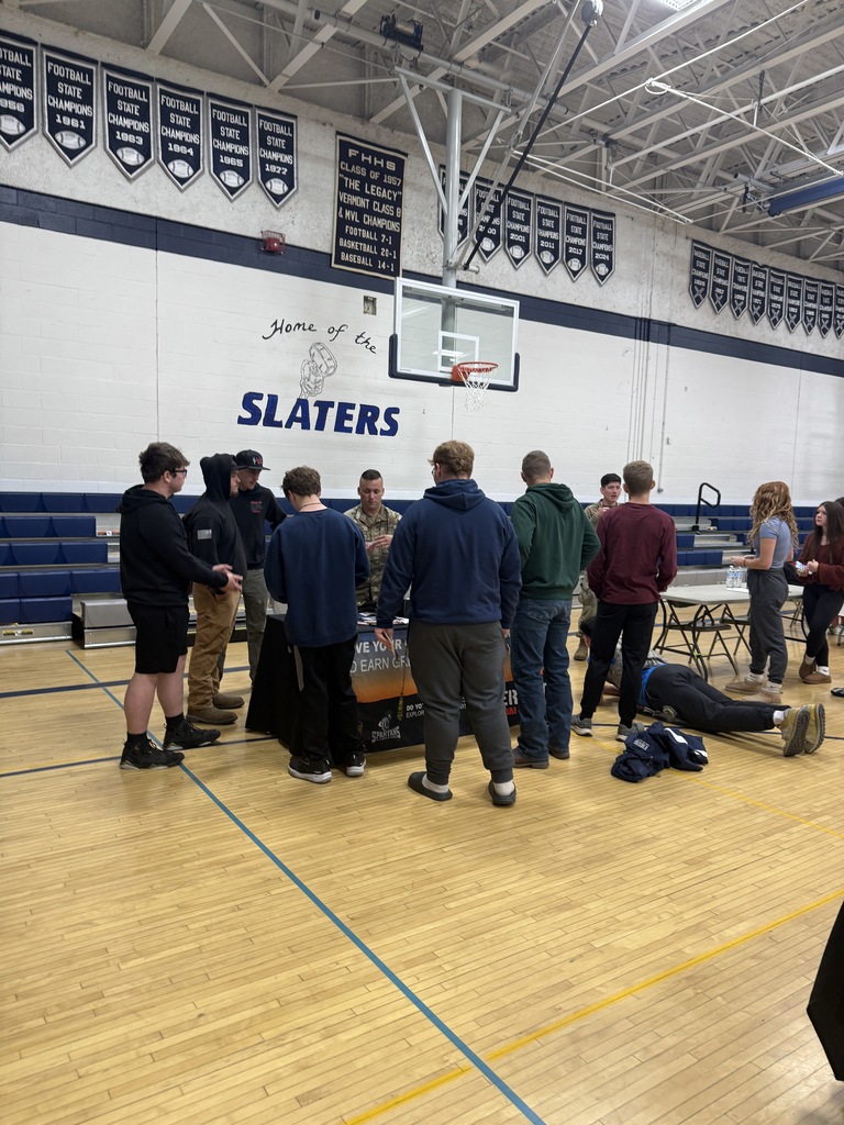 Group of students stands in front of a booth hosted by military representatives during a career fair in the Slaters’ gym.