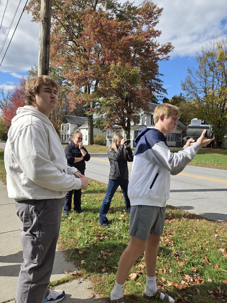 A student holds a radar device while another looks through lidar on a sunny fall day.