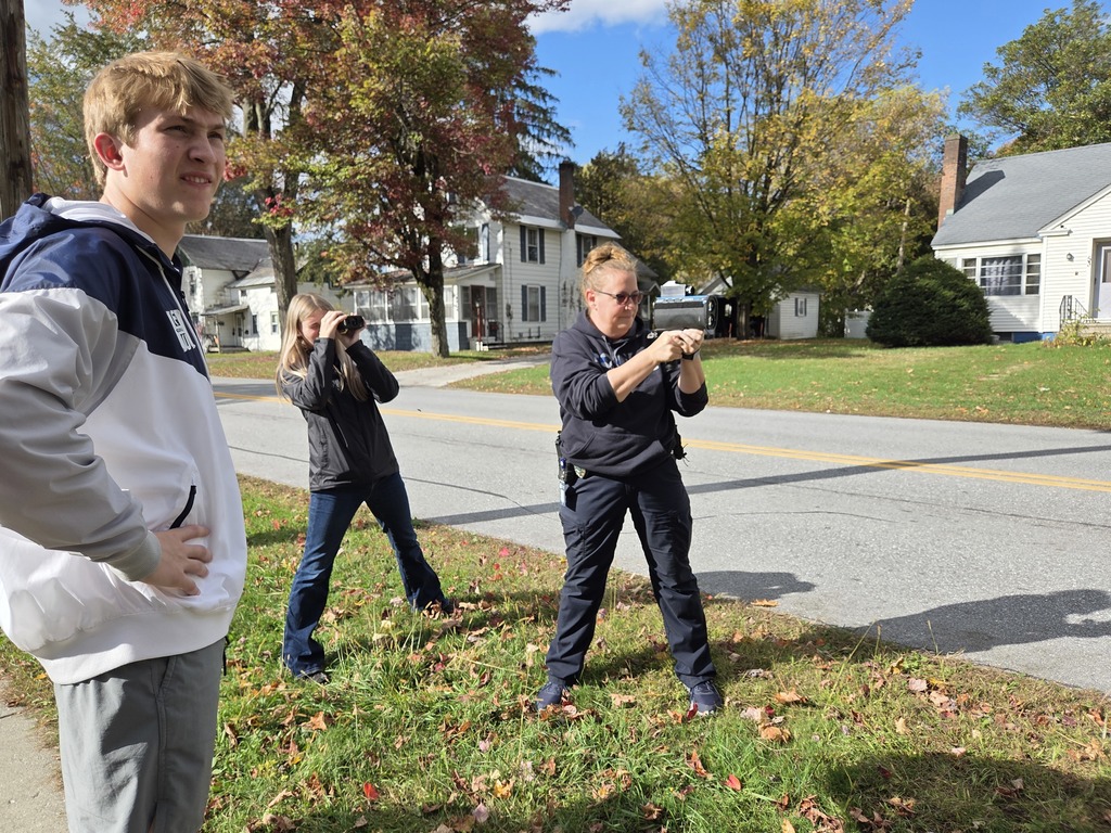 A student and the school resource officer aim radar devices as another student observes beside them.