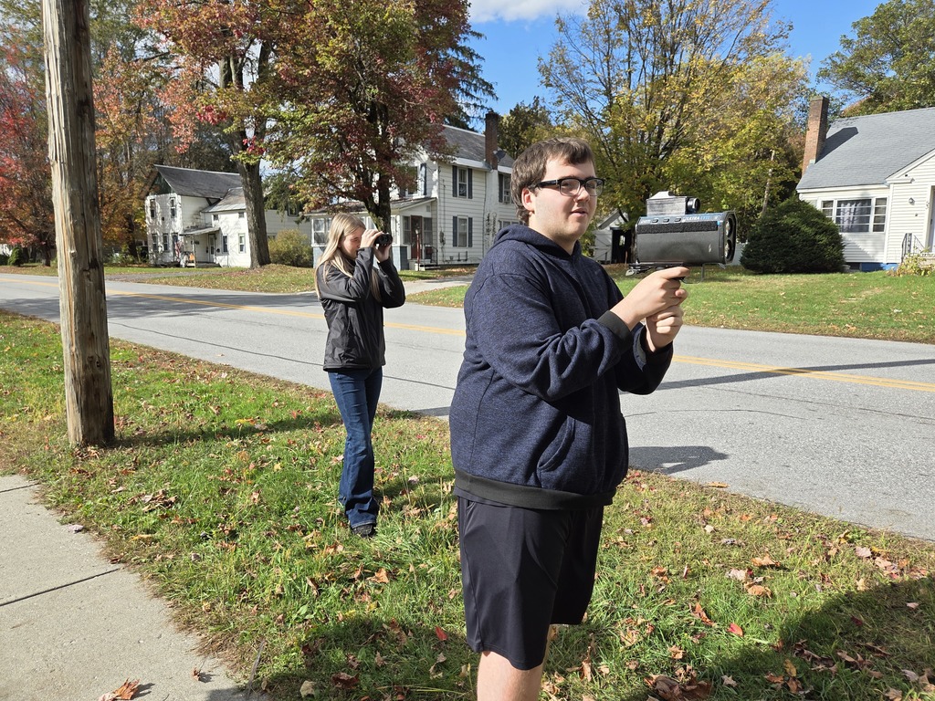 A student holds a radar device while another looks through lidar on a sunny fall day.