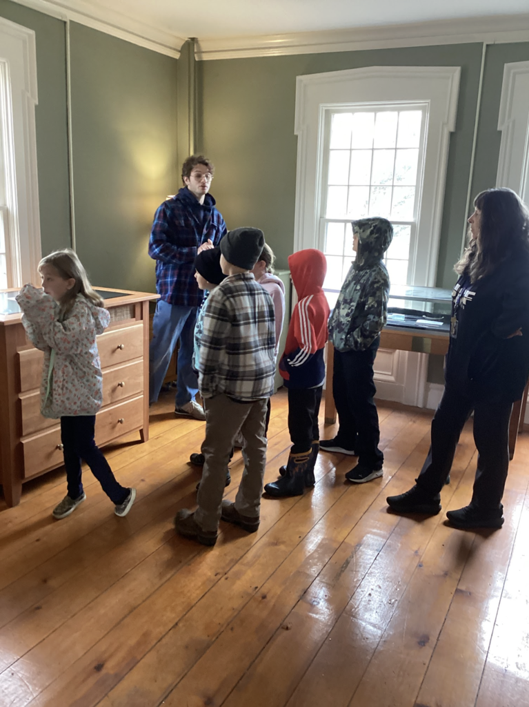 A group of children listen to a guide explaining artifacts inside a historic building.