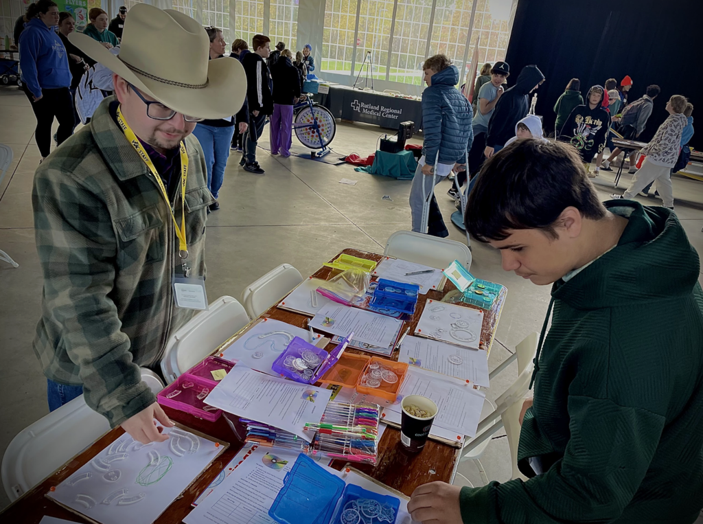 Two students explore a table of colorful science materials at a career fair.