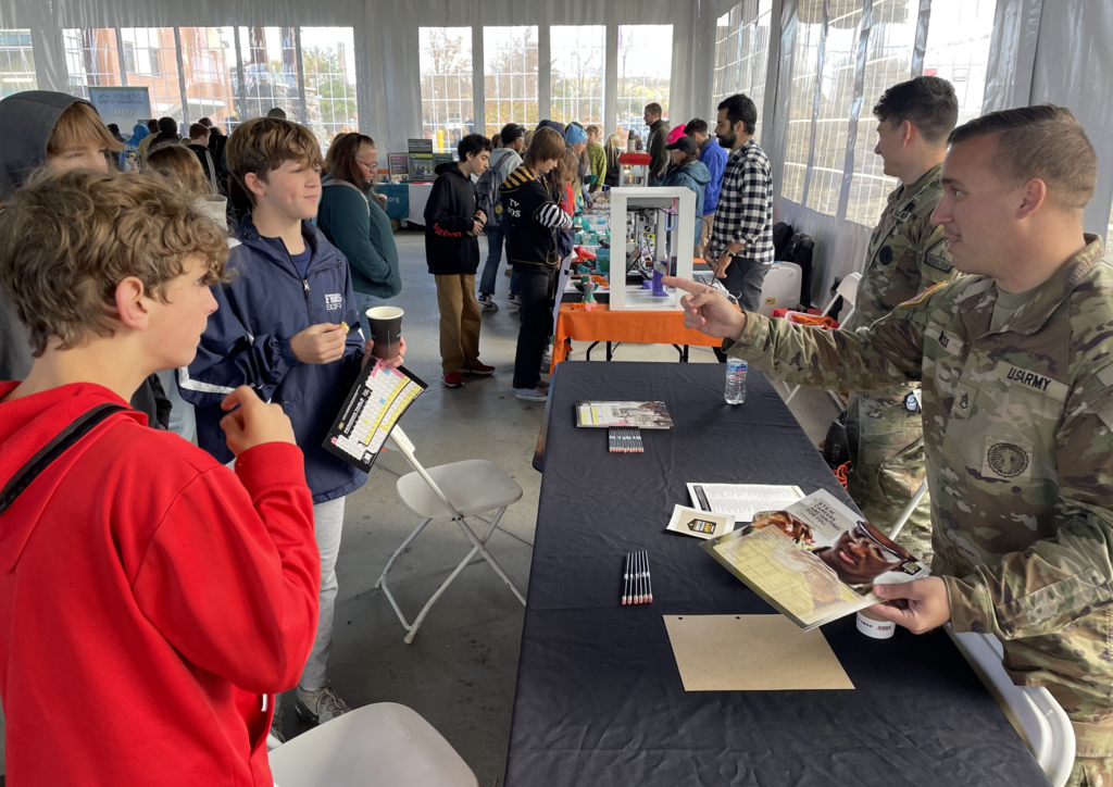 Students talk with U.S. Army representatives at a STEM fair booth.
