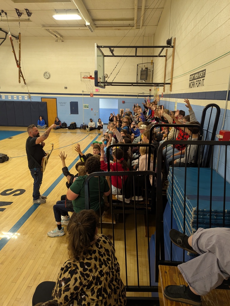 Performer engages students during the assembly as many raise their hands to participate.