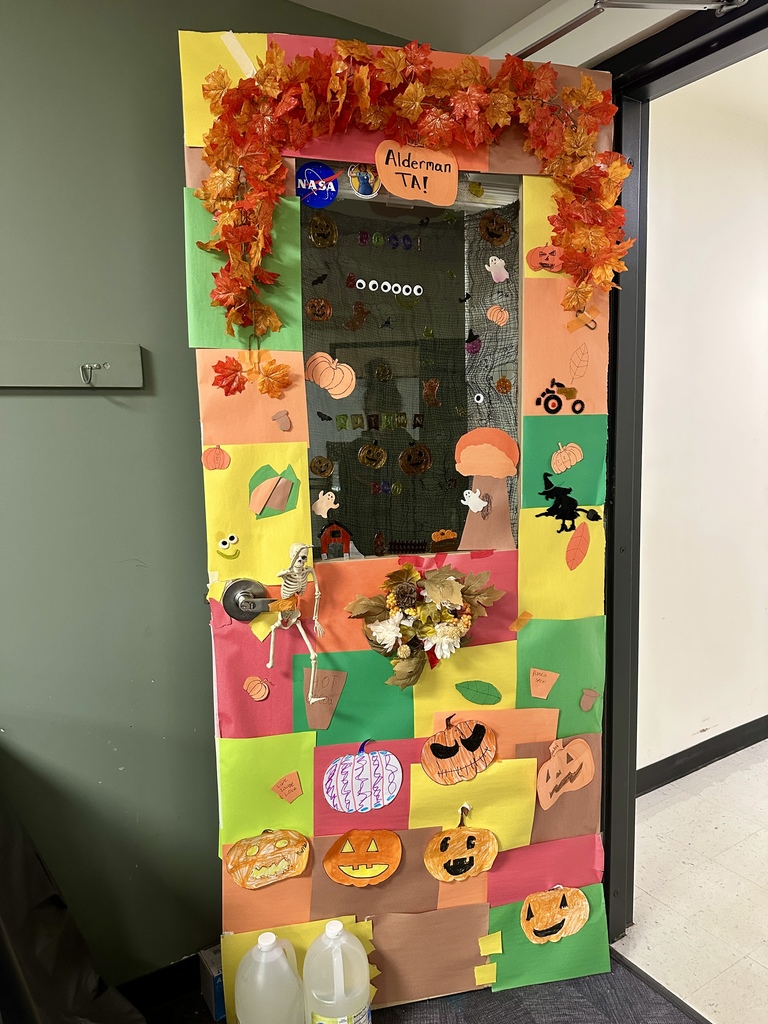 Brightly colored fall-themed door labeled “Alderman TA,” featuring paper pumpkins, leaves, a skeleton, and a wreath.