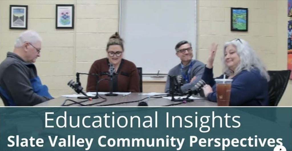 Four people sit around a table with microphones recording a podcast in a classroom setting. The image is labeled “Educational Insights: Slate Valley Community Perspectives.” The participants appear engaged in conversation, with one person smiling and waving, and another speaking into a microphone. Framed artwork decorates the wall behind them.