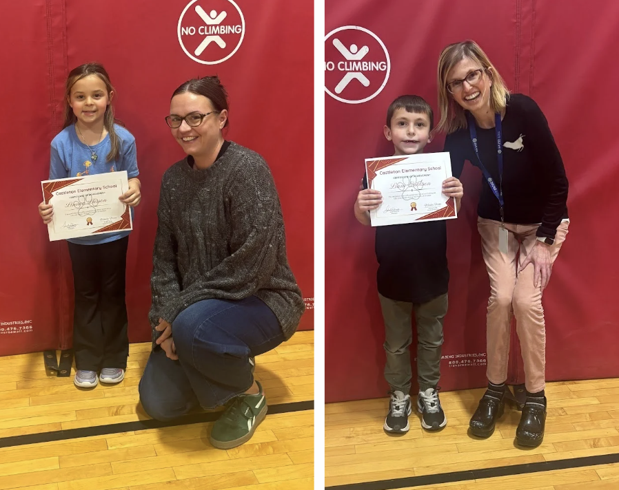 two students holding a certificate stand next to two adults in front of a red gym mat.