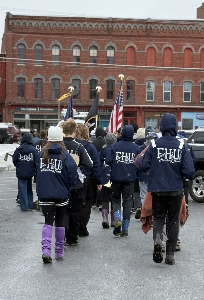 The FHU marching band walks toward downtown buildings, following the veterans’ color guard in the parade.