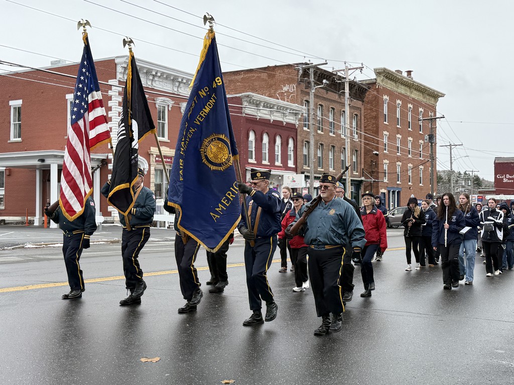 A veterans’ color guard carrying American and service flags leads the parade with the FHU marching band following behind.