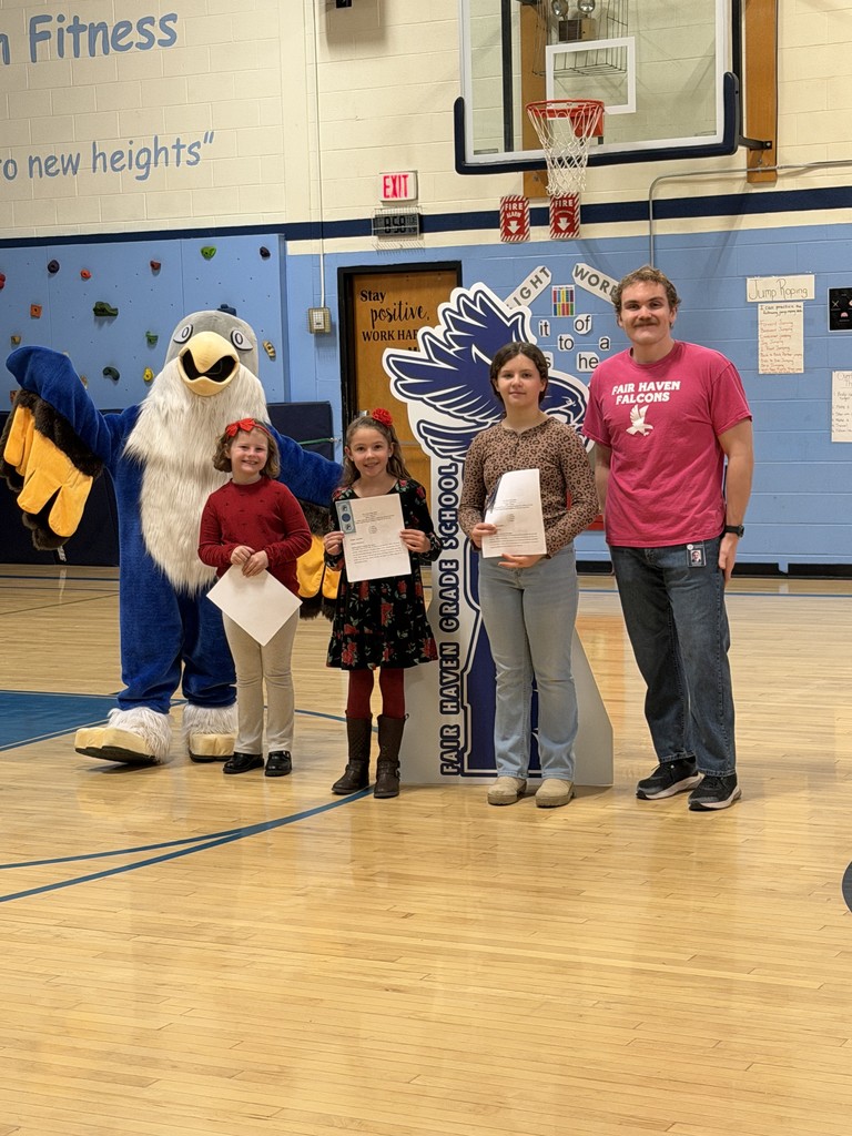 One adult, three children holding certificates, and a school mascot stand together in a gymnasium for a photo.