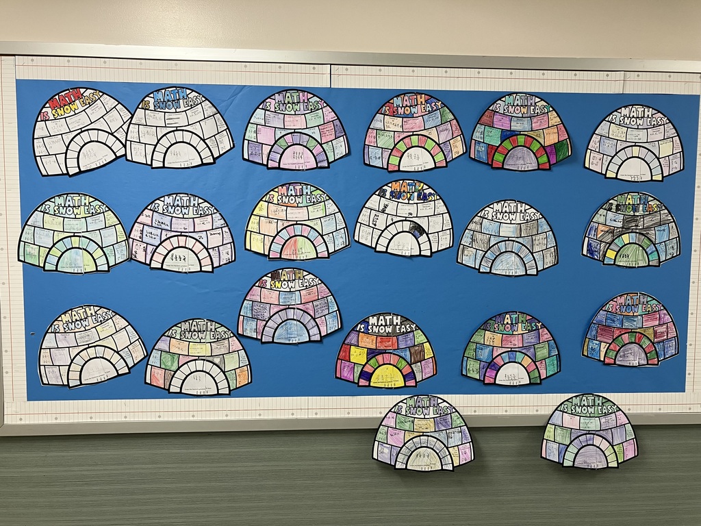A classroom bulletin board display with a light blue background, bordered by a white and red checkered pattern. The board is covered with multiple student-made projects shaped and colored like igloos, arranged in rows. Each igloo has the title "MATH IS SNOW EASY" written at the top. The igloo projects are segmented into different sections where students have written about various math skills or problems. Some igloos are partially colored in with markers or crayons, while others are mostly black and white. There are 17 igloo projects visible on the board and two placed on the ledge below.